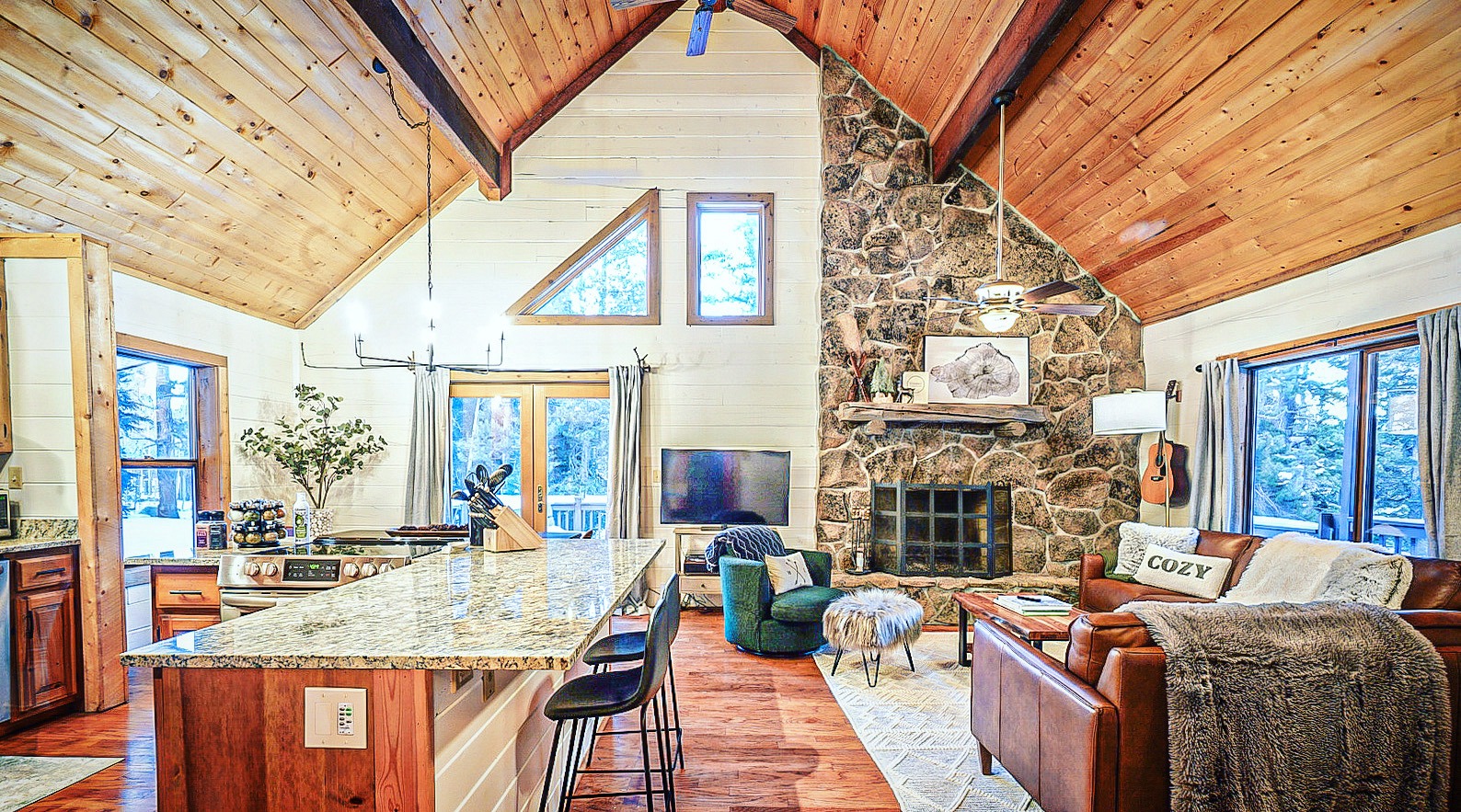 Vaulted great room with granite island, stone fireplace and pine ceiling