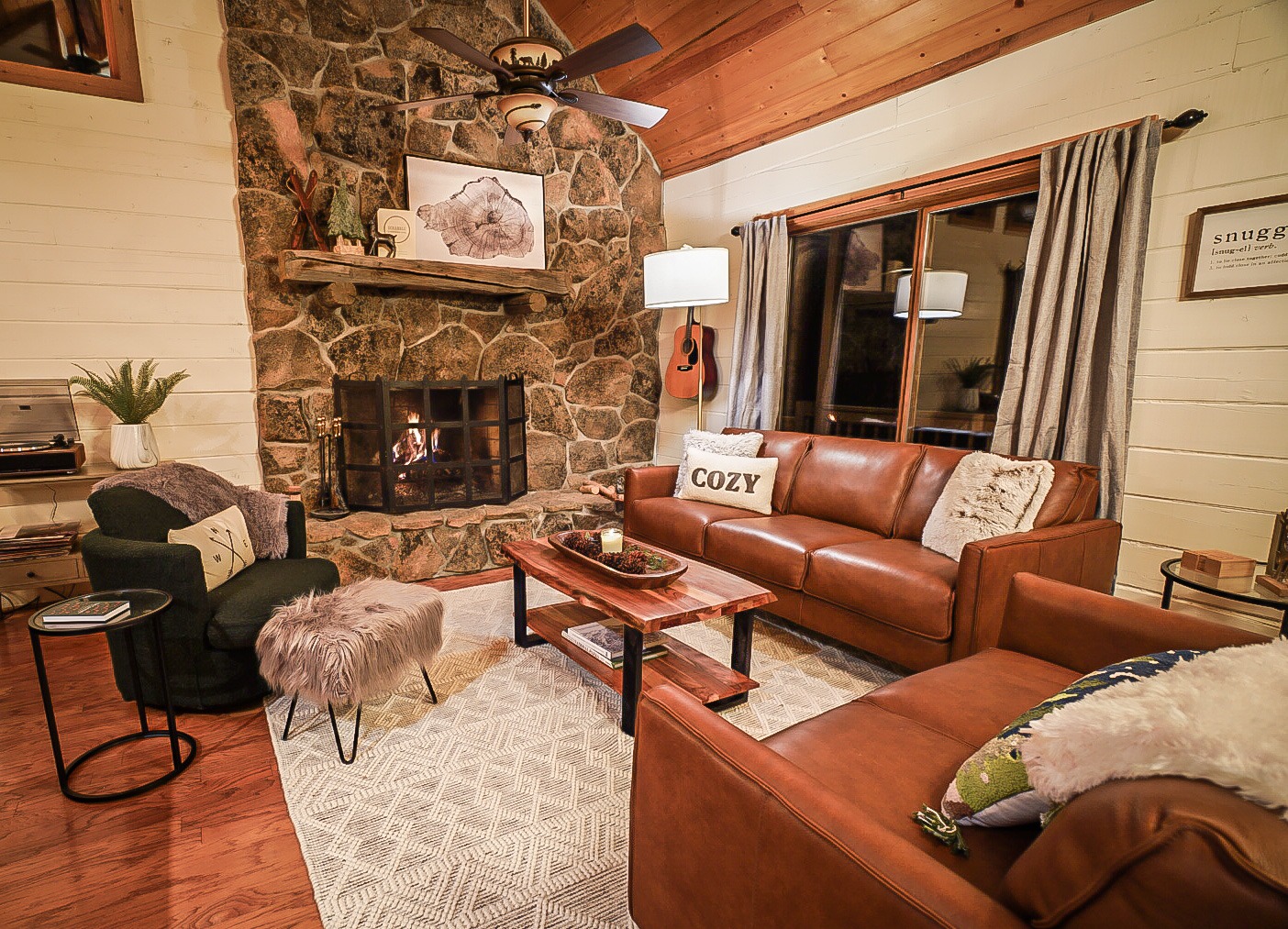 Living room with a moss-rock wood-burning fireplace and forest views